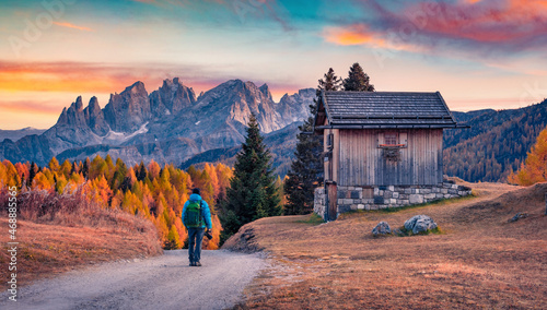 Fototapeta Naklejka Na Ścianę i Meble -  Photographer walks on the road on Fuchiade valley. Splendid evening view of Dolomite Alps, Italy, Europe. Amazing autumn sunset in Italy, Europe. Traveling concept background..