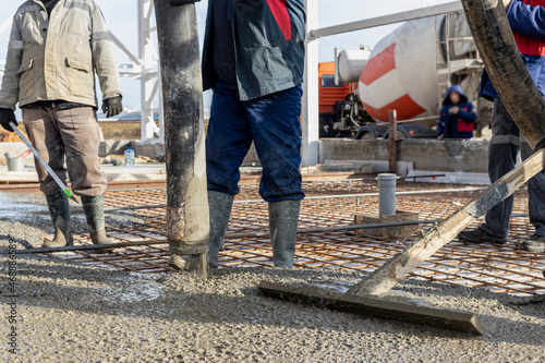 A construction worker is finishing and leveling the concrete surface of the foundation at a construction site.