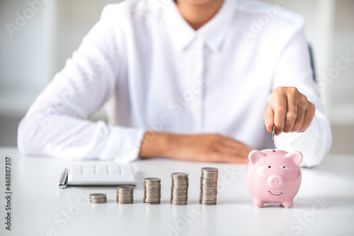 business woman holding a coin in a piggy bank On a table with sunlight. Money Saving Ideas for Financial Accounting