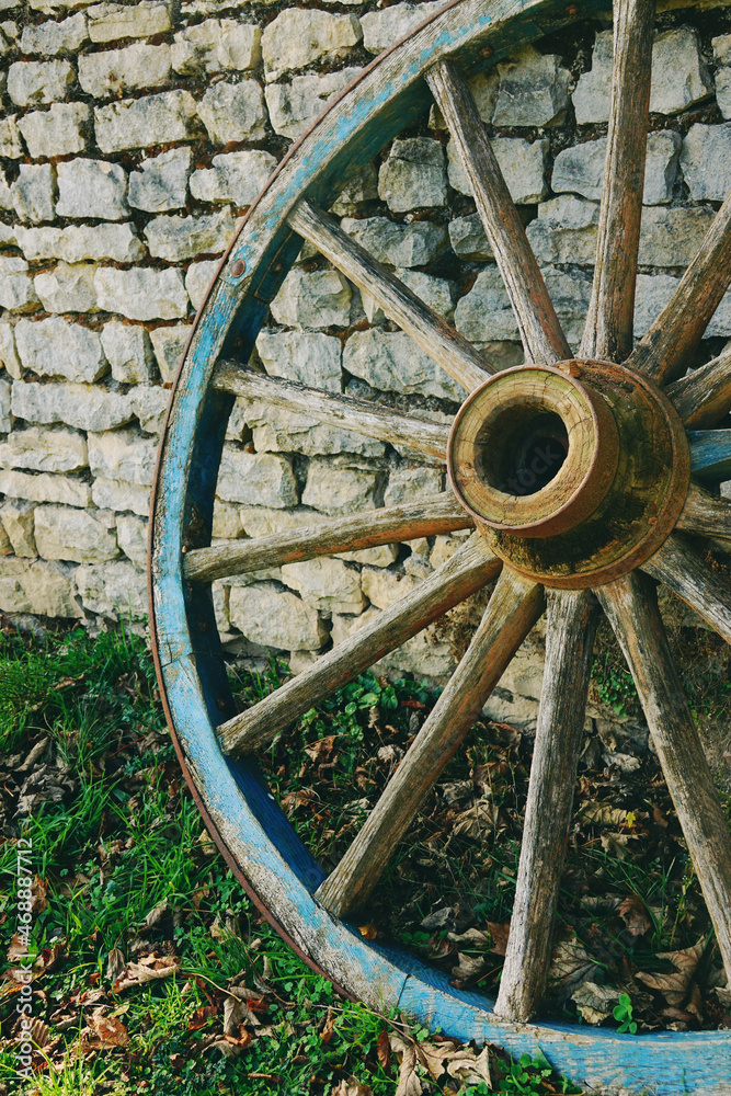 Old wooden wheel wagon as a garden decor in a medieval village of France with stone walls