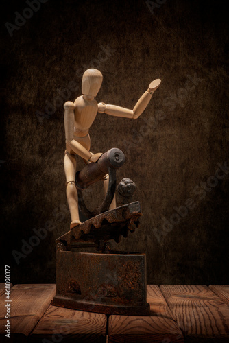 A wooden man and an old rusty metal iron on a wooden table and an artistic background.