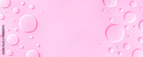 banner round drops of transparent gel serum on pink background with place for text	
 photo