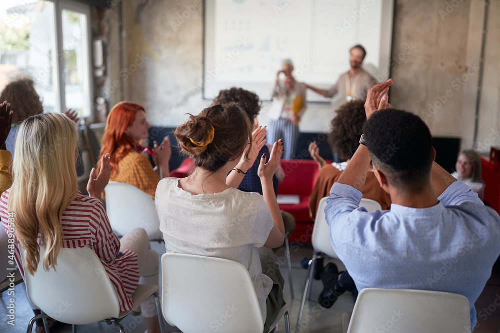 A group of young creative people is satisfactorily applauding the well-held presentation in the office