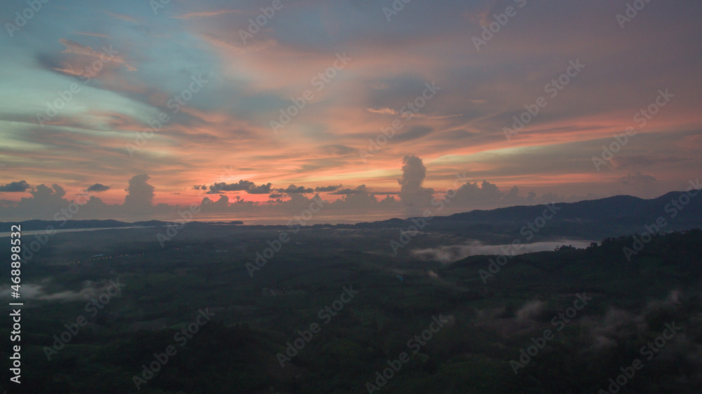 aerial view scenery sunrise mist above the mountain in tropical rainforest..slow floating fog blowing cover on the top of mountain look like as a sea of mist. .beautiful sunrise in the mist background