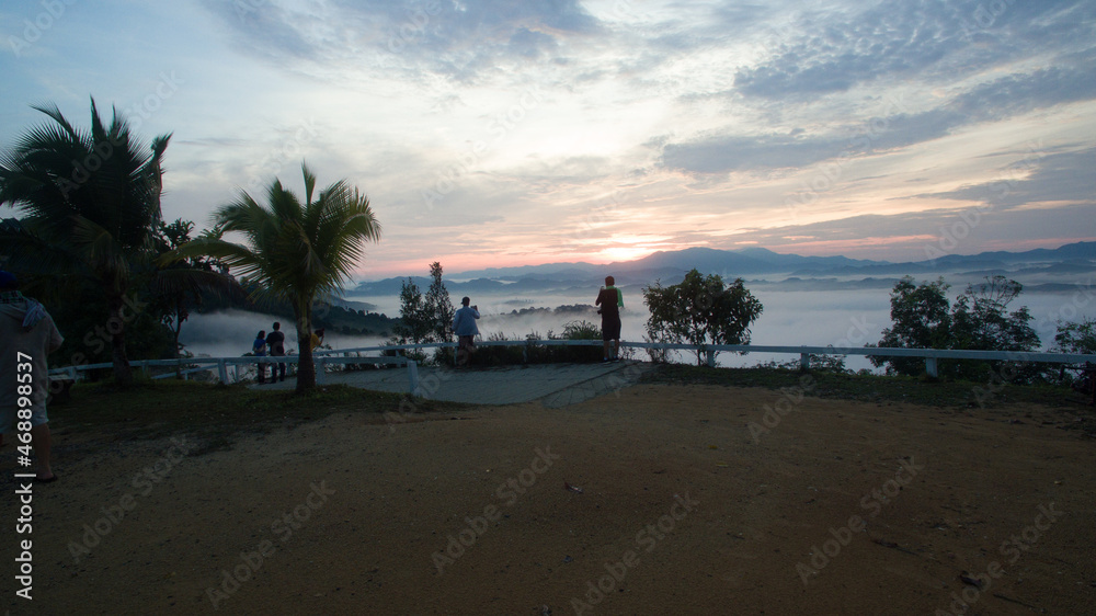 aerial view scenery sunrise mist above the mountain in tropical rainforest..slow floating fog blowing cover on the top of mountain look like as a sea of mist. .beautiful sunrise in the mist background
