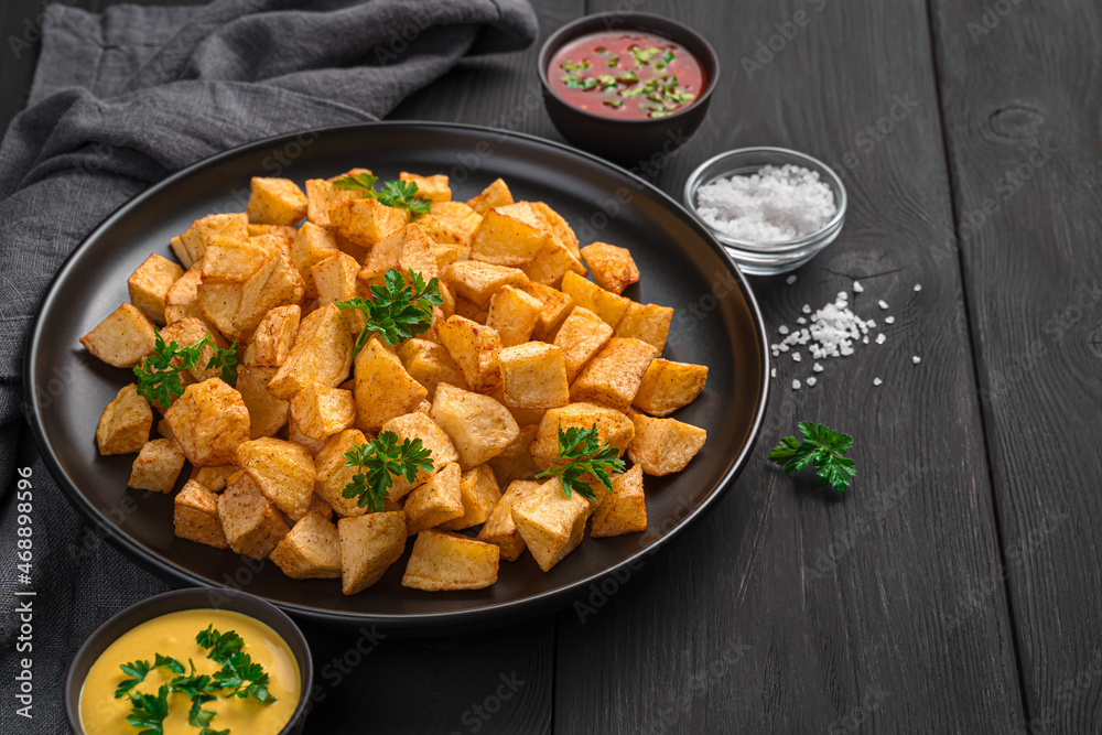 Patatas bravas with hot sauces on a black background. Patatas bravas with hot sauces on a black background.