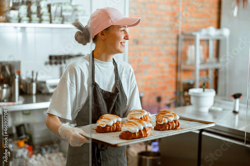 Pretty woman baker holds beautiful croissants with burnt albumenous cream in shop photo