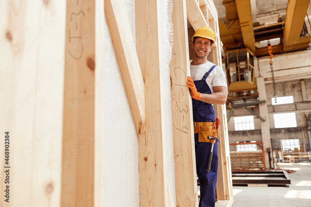 Cheerful male worker standing in wooden construction cabin