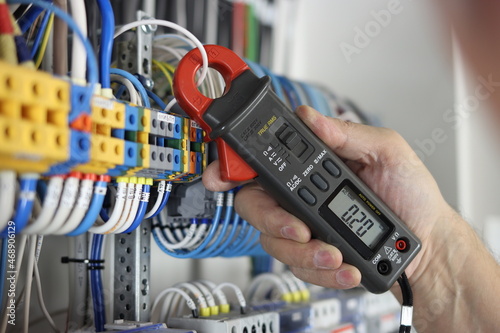 An electrical engineer uses a multimeter to check the electrical parameters in the control panel for process control.