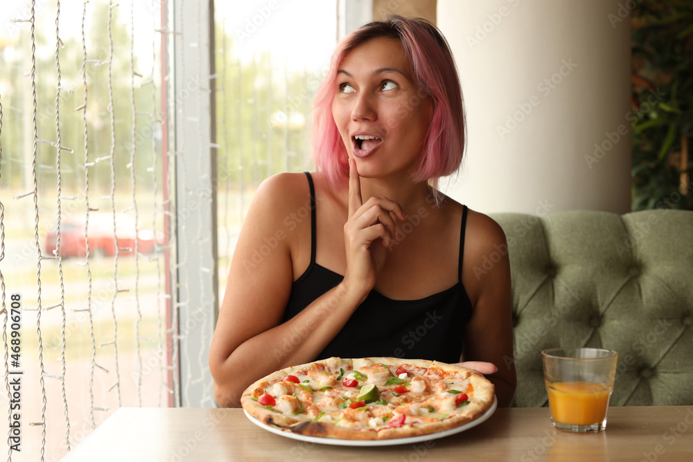 A cheerful girl is going to eat a seafood pizza