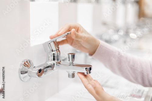 Canvastavla Pretty young woman choosing a bathroom/kitchen tap in a home furnishings retail