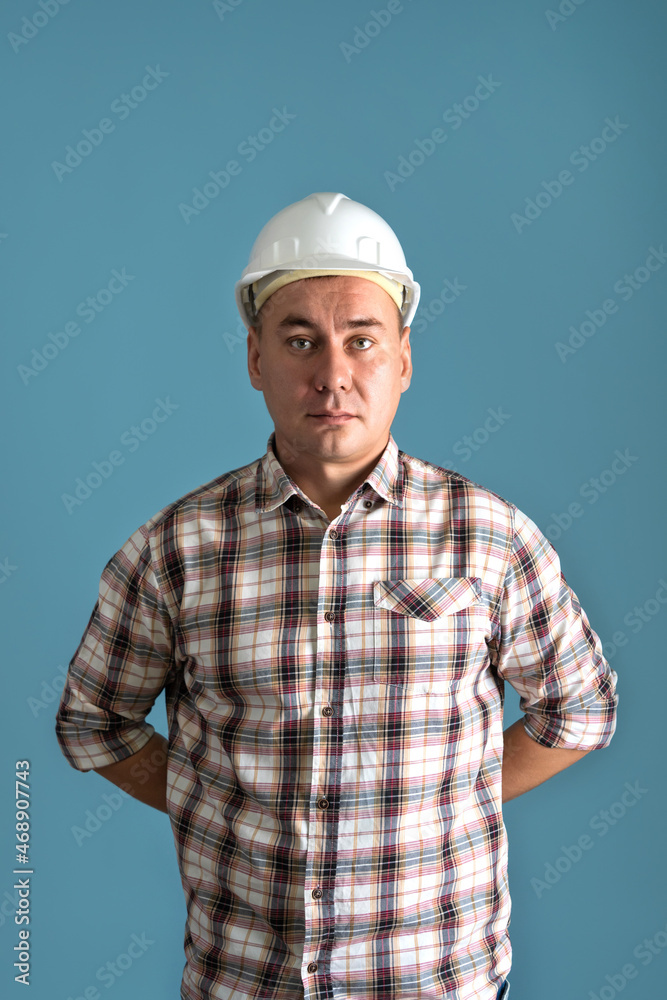 A construction worker in a shirt and a white helmet on a blue background A construction worker in a shirt and a white helmet on a blue background