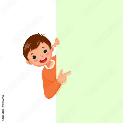 little boy standing behind blank board peeking and pointing to empty banner with finger.