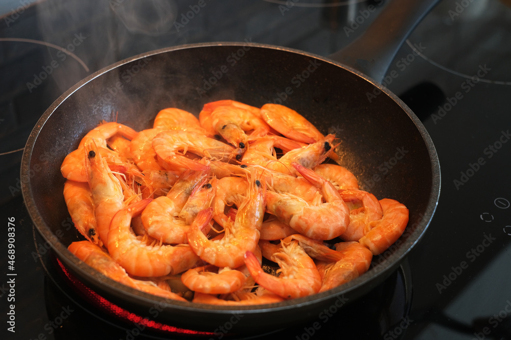 the cook fries shrimps in garlic sauce in a frying pan close-up. asian shrimp in sauce close-up the cook fries shrimps in garlic sauce in a frying pan close-up. asian shrimp in sauce close-up