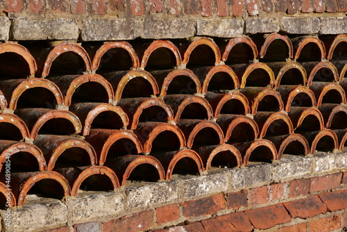 Ornate wall comprising old bricks and terracotta semi circular tiles