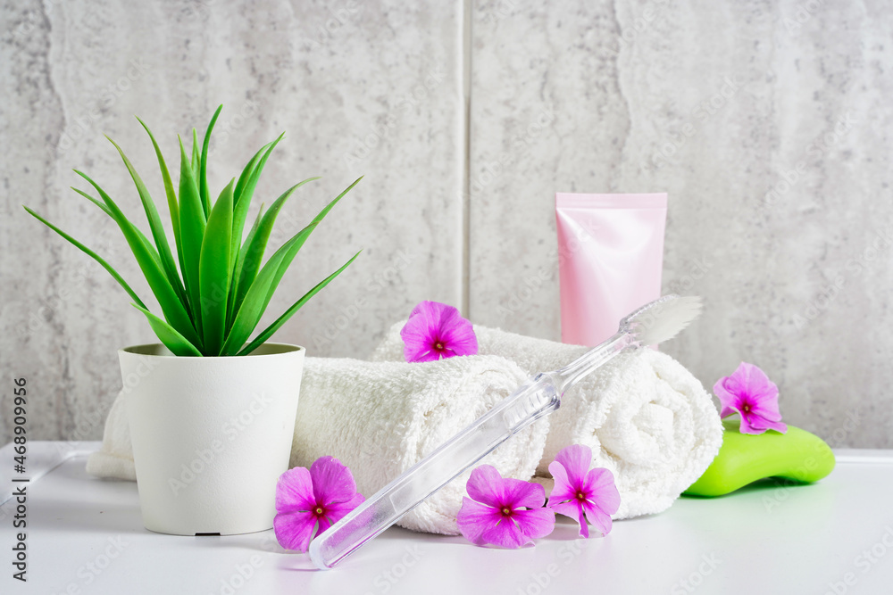 Toothbrush, toothpaste and white towels, pink flowers with copy space. Aromatherapy and Oral care, body hygiene and morning daily routines. Toothbrush, toothpaste and white towels, pink flowers with copy space. Aromatherapy and Oral care, body hygiene and morning daily routines.