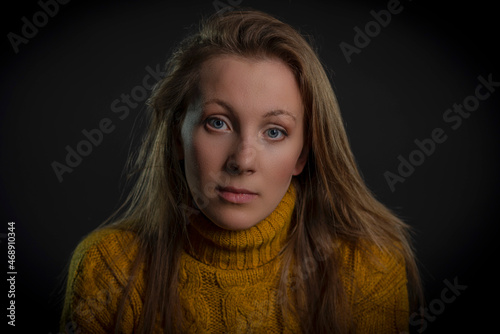 portrait of a young woman in a yellow sweater on a black background