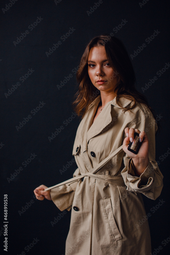 young beautiful girl in the studio, on a black background, she is wearing a trench coat and black lingerie young beautiful girl in the studio, on a black background, she is wearing a trench coat and black lingerie
