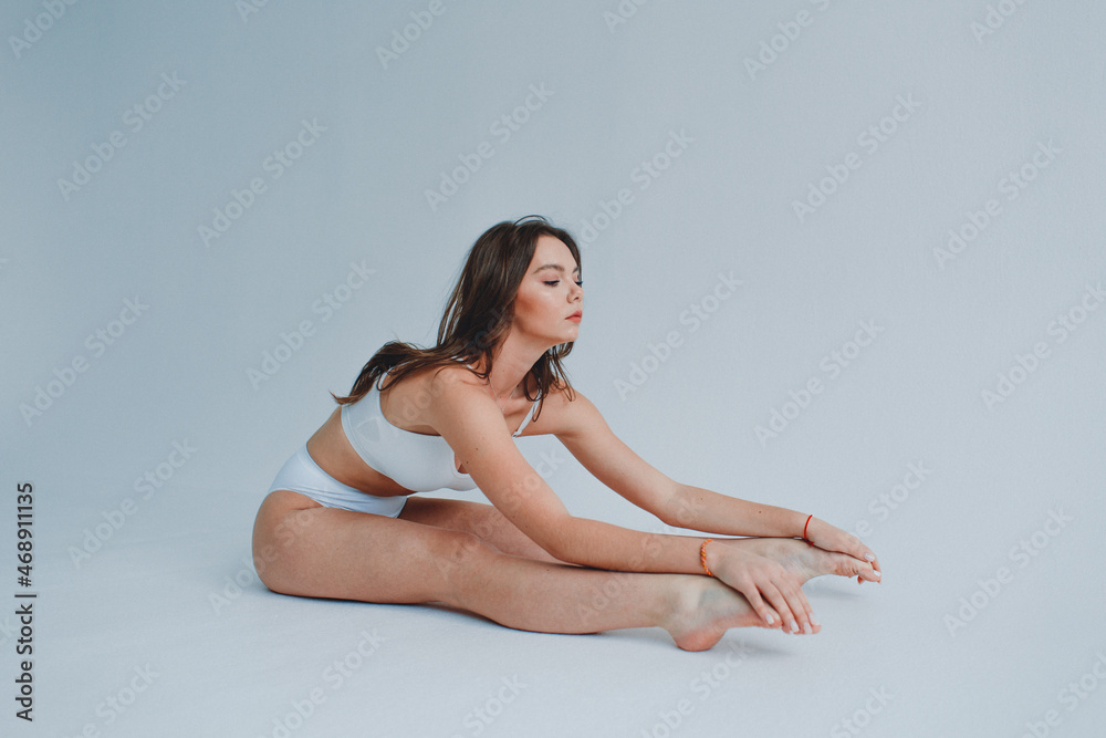 girl gymnast, in a white uniform, panties and top, in the studio on a white background shows exercises girl gymnast, in a white uniform, panties and top, in the studio on a white background shows exercises