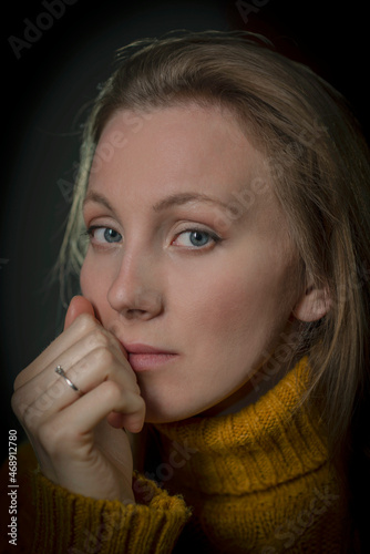 portrait of a young woman in a yellow sweater on a black background