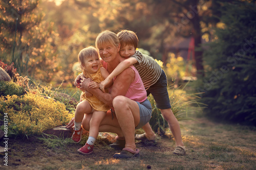 Family portrait of grandmother and her grandson and his little sister in summer. Image with selective focus and toning