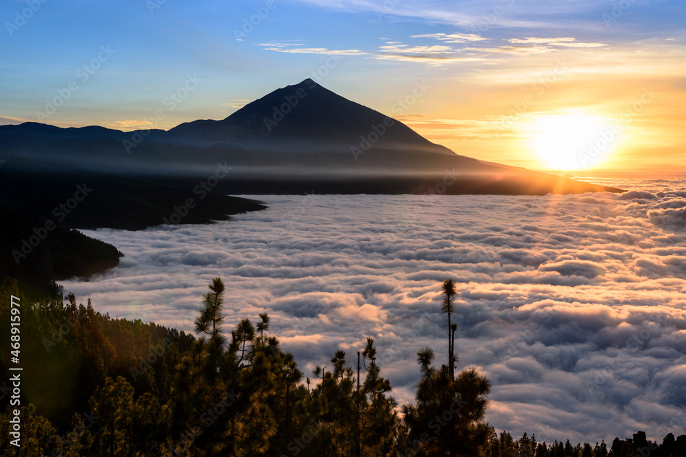 Teide volcano rises majestically above a lake in the evening light shining clouds, Tenerife, Spain