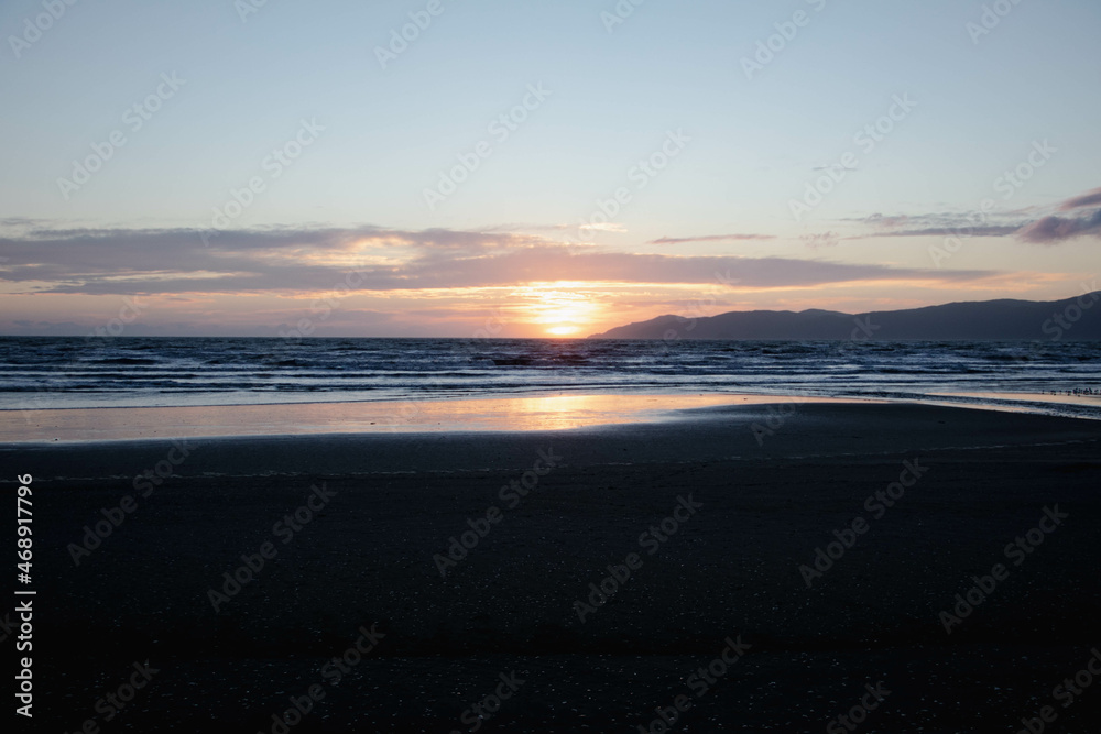 Atardecer en la playa con el reflejo del sol en la arena de Nueva Zelanda