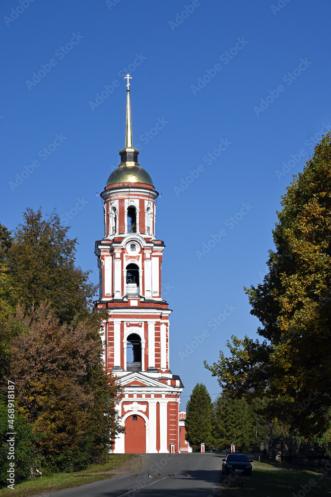 The brick bell tower of the ancient Orthodox Cathedral of the Resurrection of Christ stands surrounded by trees in the ancient city of Staraya Russa, Novgorod region.  Ancient Russian architecture of 