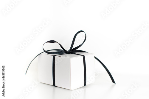 Black Friday sale with stylish gift box present and black ribbon on white background, flat lay, top view, copy space. Black friday concept. Shopping concept and black Friday composition.