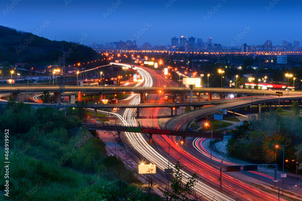 Multilevel road junction with cars moving along it in the night city.