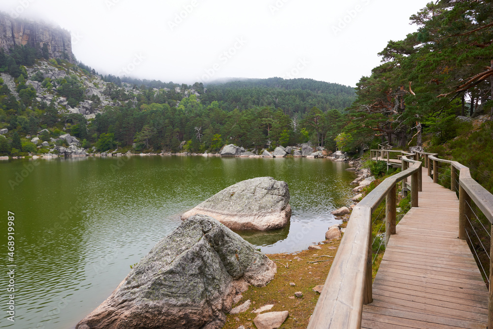 A lake with rock formations and surrounded by a pine forest.