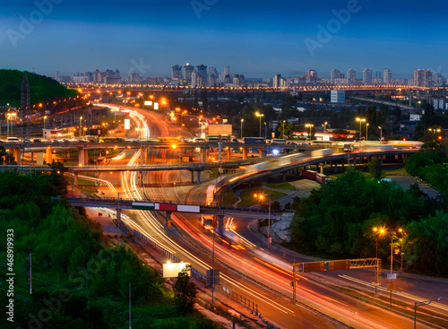 Multilevel road junction with cars moving along it in the night city. © Michael
