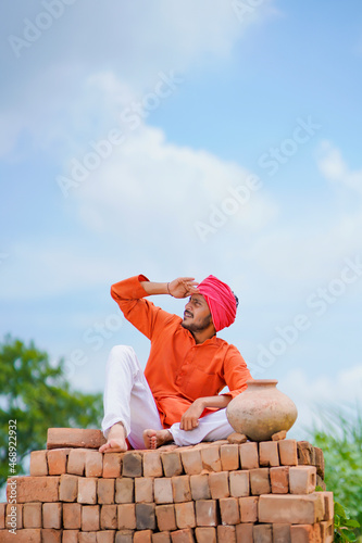 Indian farmer sitting on bricks and watching on sky