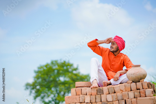 Indian farmer sitting on bricks and watching on sky