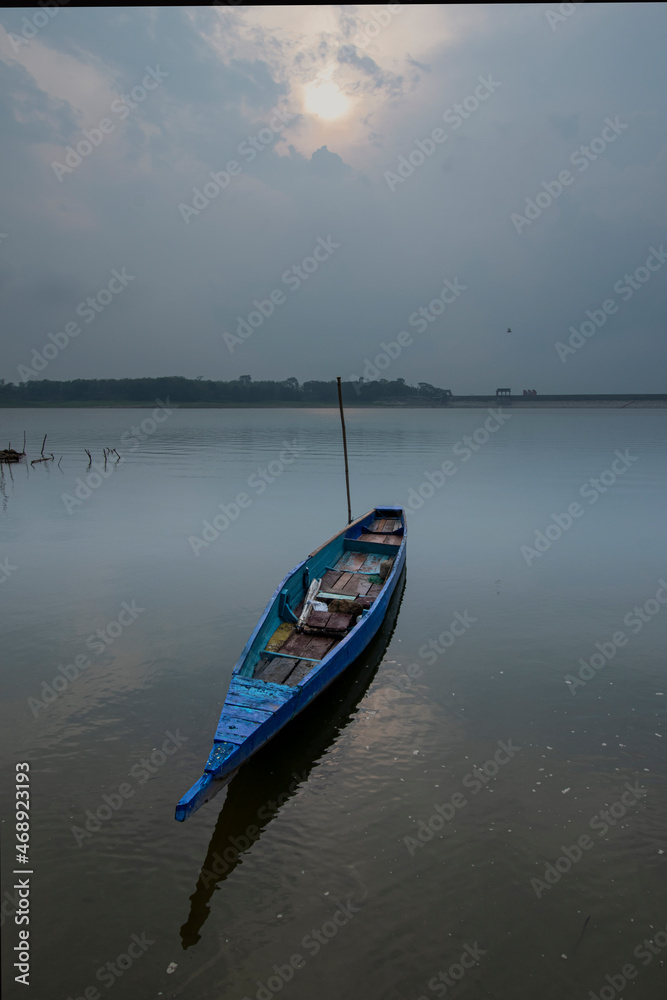 Traditional fishing boat floating on the lake, cloudy sky background Traditional fishing boat floating on the lake, cloudy sky background