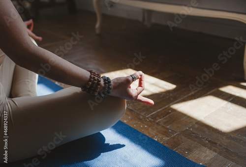 Close-up of a girl sitting on a yoga mat in the lotus position in the classroom facing the sun. healthy lifestyle