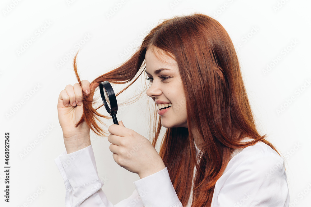 cheerful red-haired woman holding a magnifying glass near her face cheerful red-haired woman holding a magnifying glass near her face