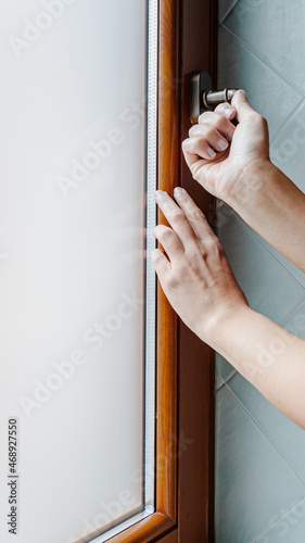 Woman opening window indoors, closeup. Wooden window of the bathroom