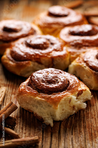 Homemade sweet cinnamon buns on a wooden table, close up view