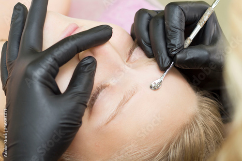 Procedure for cleaning skin with steel tool from blackheads and acne. Deep cleansing of the female face with blackhead remover in the beauty salon. Cosmetologist making receiving cleansing therapy