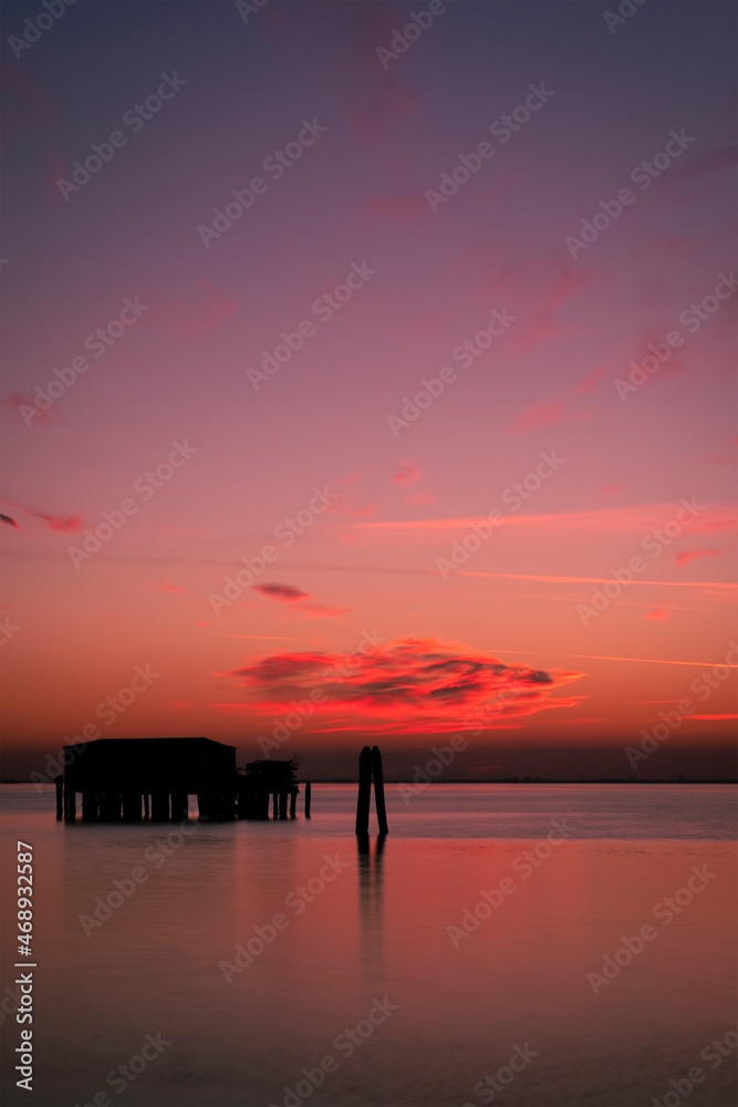 Fototapeta premium Sunset on the Venetian lagoon with the fishermen's houses, Pellestrina island, Venetian lagoon, Italy