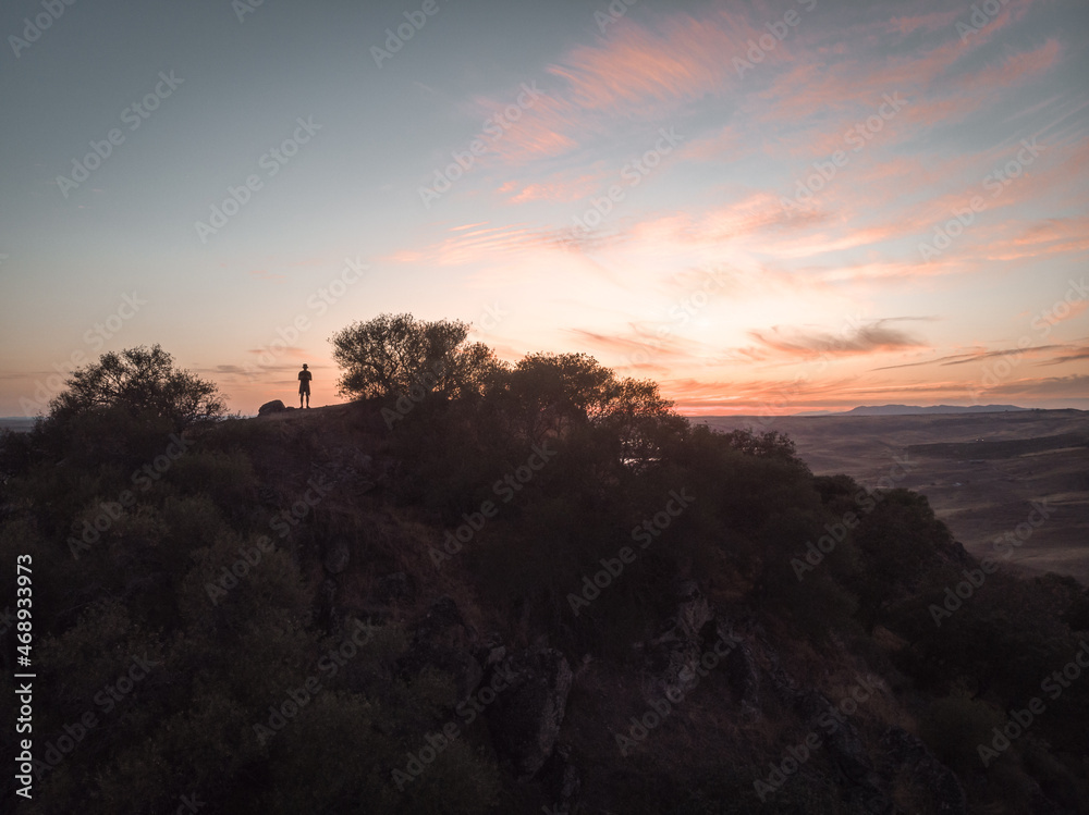Aerial drone photo, stunning sunset illuminates the Cerro Masatrigo in Extremadura. Hiker standing on edge and observing the water landscape. Man watching the sunrise in the mountains.