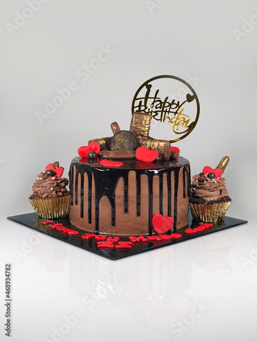 Chocolate cake with fresh chocolates decorated as topping, red edible hearts and chocolate ganache photo