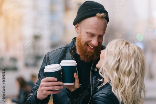 Romantic couple drinking coffee in city. Close up. Young man and woman in leather jackets hugging on date.