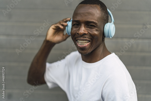 Young cool black male smiling while putting on blue headphones photo