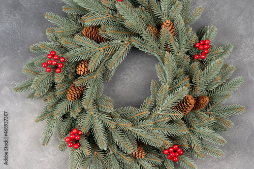 top view of decorative festive wreath with red winter berries and pine cone.