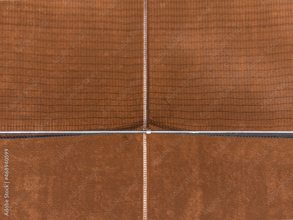 Fototapeta premium Detail of net shadow at gravel clay tennis court seen from above. Drone aerial top down shot