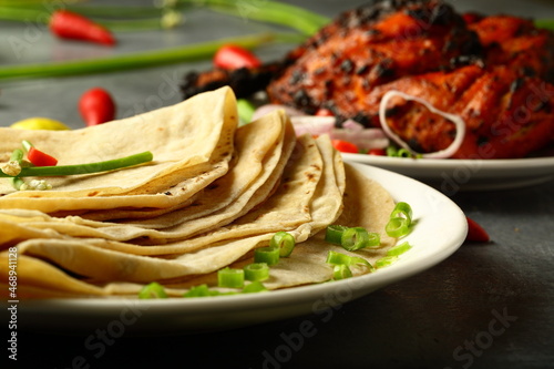Healthy Indian meal-  whole wheat chapattis served with grilled chicken on a rustic kitchen table. photo