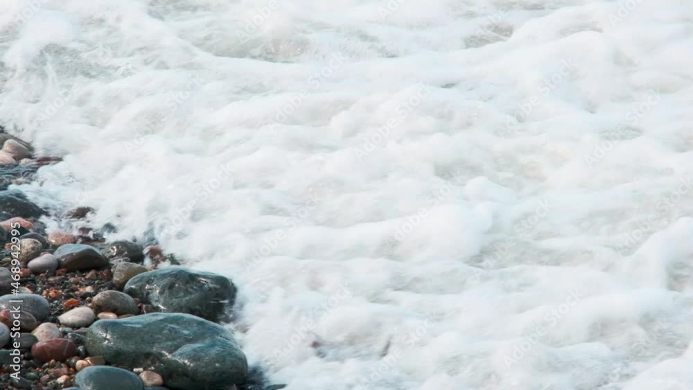 sea waves with foam crash powerfully on the shore in storm and wash the coast of pebbles and small stones sea waves with foam crash powerfully on the shore in storm and wash the coast of pebbles and small stones