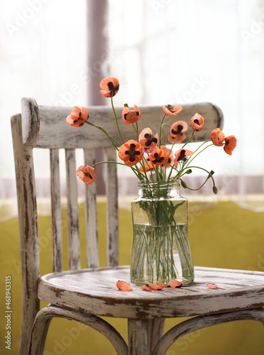 A Little Red Poppies Bouquet Arranged In Classical Style Stillife of popies in a glasses vase on vintage hair photo